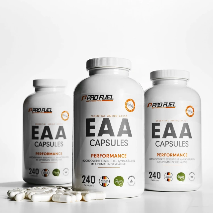 Trzy białe słoiki ProFuel EAA Capsules ustawione na jasnym tle, przed nimi rozsypane białe kapsułki. Na etykietach pomarańczowy napis Performance i logo ProFuel.